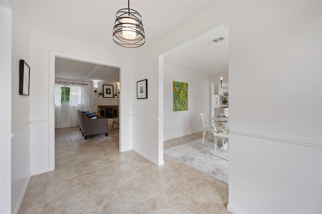 hall featuring baseboards, visible vents, and light tile patterned flooring