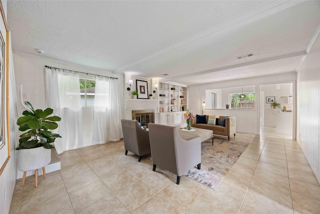 living area featuring a wealth of natural light, a textured ceiling, light tile patterned floors, and crown molding