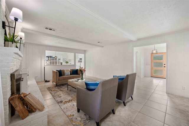 living area featuring light tile patterned flooring, a textured ceiling, visible vents, and a fireplace