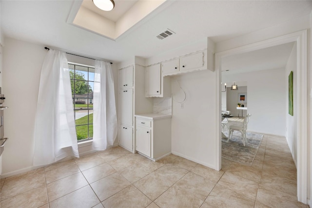 kitchen featuring light tile patterned flooring, light countertops, white cabinets, baseboards, and visible vents