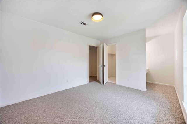 unfurnished bedroom featuring baseboards, visible vents, and light colored carpet