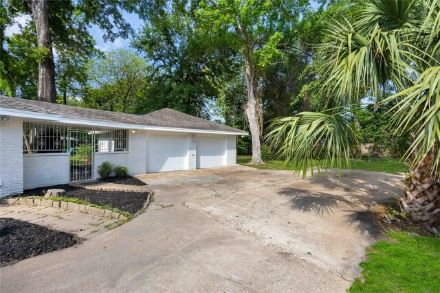 view of home's exterior featuring an attached garage, driveway, and brick siding