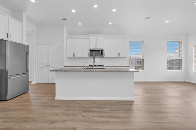 31411 Raleigh Creek Dr, Tomball, TX 77375 - kitchen with stainless steel appliances, an island with sink, recessed lighting, dark stone counters, and decorative backsplash