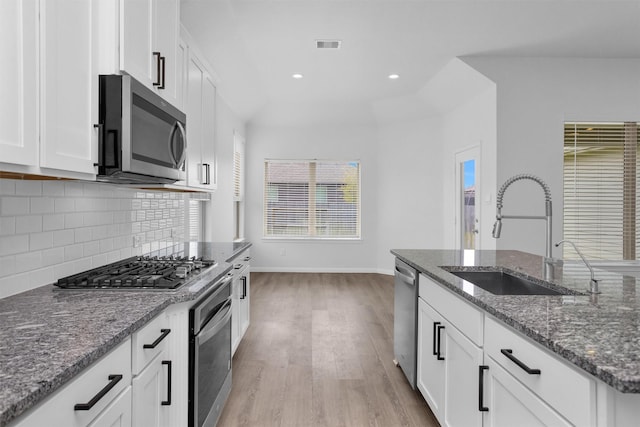 31411 Raleigh Creek Dr, Tomball, TX 77375 - kitchen featuring stainless steel appliances, a sink, light wood-type flooring, tasteful backsplash, and white cabinets