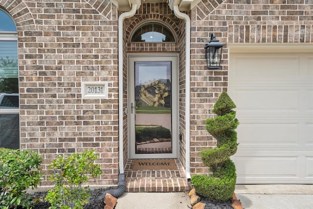 property entrance with brick siding and an attached garage