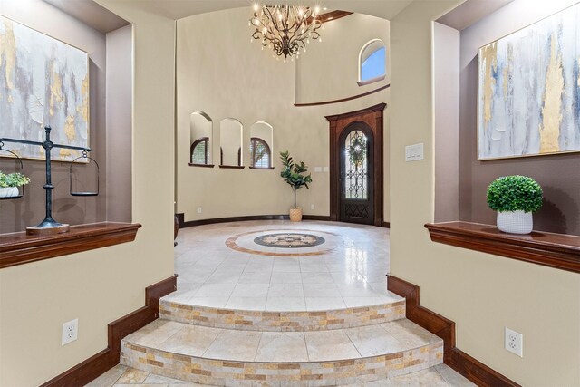 entryway featuring baseboards, a notable chandelier, and tile patterned floors