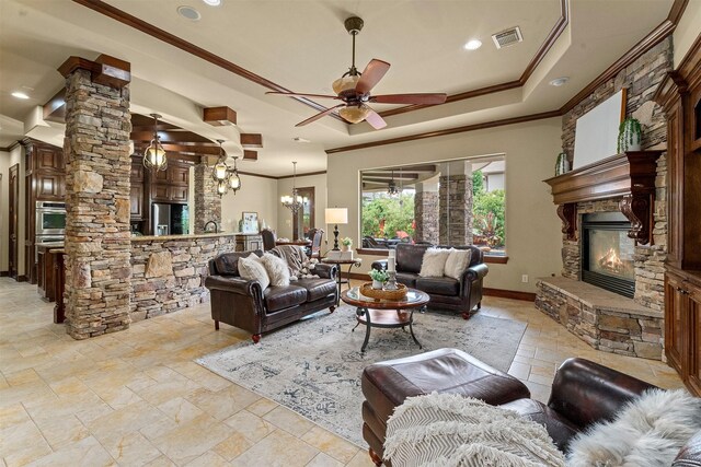 living room with stone tile floors, a stone fireplace, decorative columns, and ornamental molding