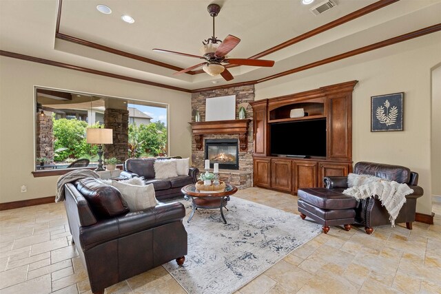 living room featuring crown molding, ceiling fan, a raised ceiling, stone tile floors, and visible vents