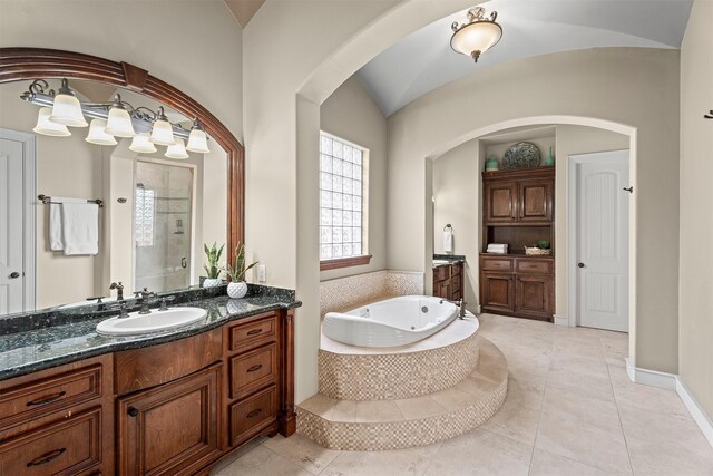bathroom featuring a jetted tub, baseboards, two vanities, a shower stall, and a sink