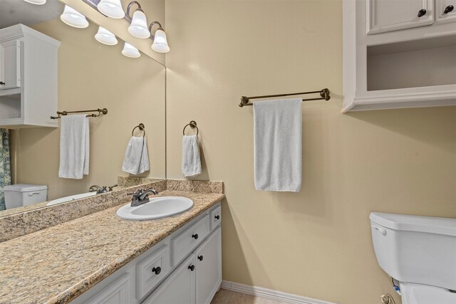 bathroom with baseboards, vanity, and toilet