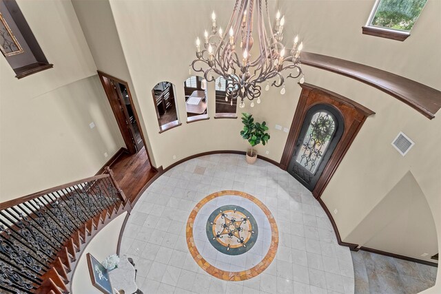 entryway featuring a towering ceiling, tile patterned floors, a chandelier, and visible vents