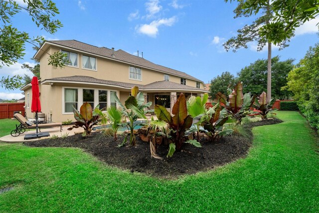 back of house with a patio, stucco siding, fence, and a yard