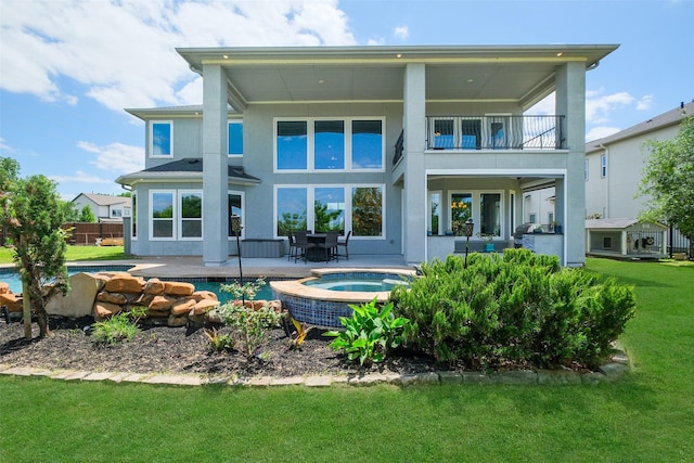 back of house featuring a patio area, a balcony, a lawn, fence, and an in ground hot tub