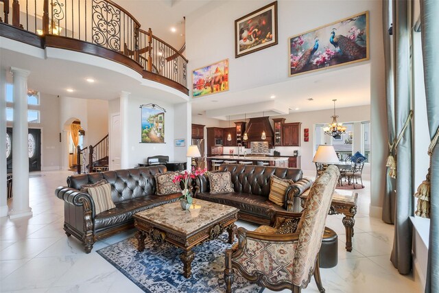 living area with arched walkways, decorative columns, a high ceiling, marble finish floor, and stairway