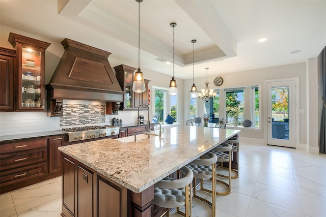 kitchen featuring a raised ceiling, light stone countertops, custom exhaust hood, and decorative backsplash