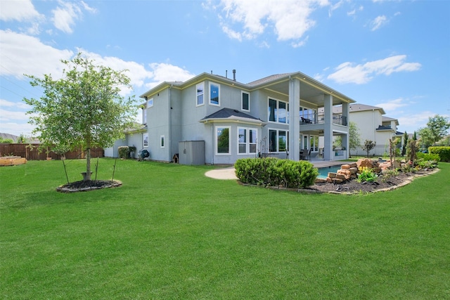 rear view of house featuring a yard, a patio area, a balcony, and fence