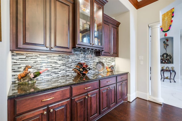 bar with dark wood finished floors, baseboards, backsplash, and ornate columns