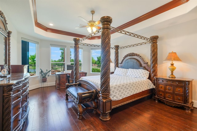 bedroom with a tray ceiling, dark wood finished floors, baseboards, and ornamental molding