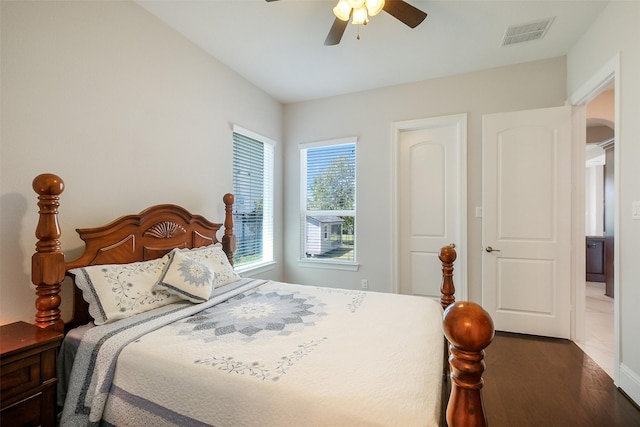 bedroom featuring wood finished floors, visible vents, arched walkways, and a ceiling fan