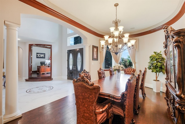dining space featuring arched walkways, baseboards, a notable chandelier, and decorative columns