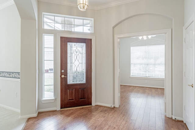 entryway featuring baseboards, crown molding, hardwood / wood-style flooring, and a notable chandelier
