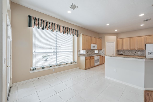 kitchen featuring backsplash, visible vents, and white appliances