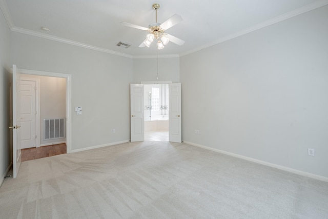 empty room with visible vents, ornamental molding, light colored carpet, and ceiling fan