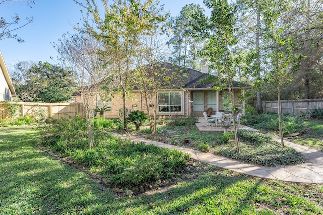 view of front of home featuring brick siding, a patio area, a front yard, and fence