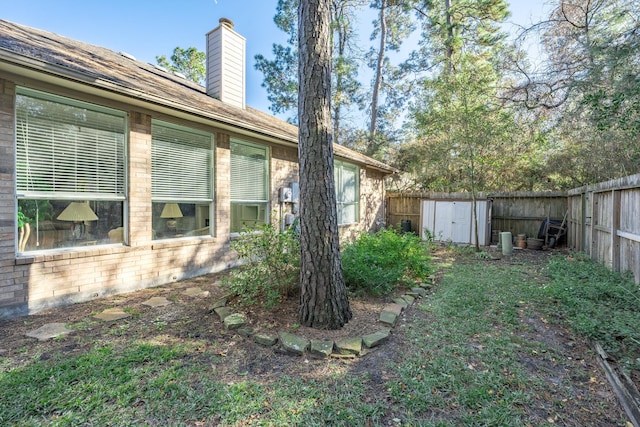 view of yard with a fenced backyard, an outbuilding, and a storage shed