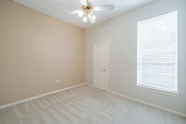 unfurnished room with light carpet, baseboards, ceiling fan, and plenty of natural light