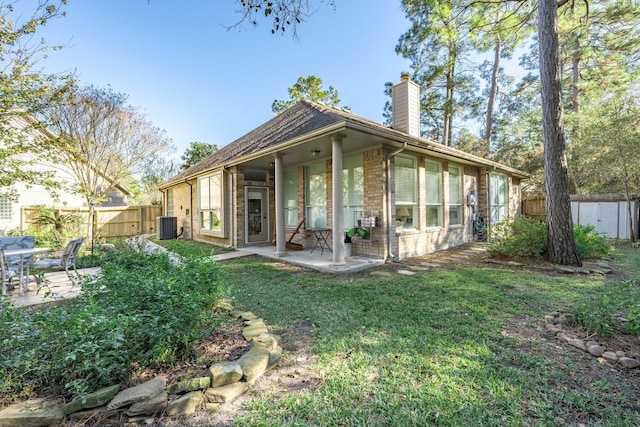 rear view of house with a fenced backyard, a chimney, brick siding, a patio area, and a lawn