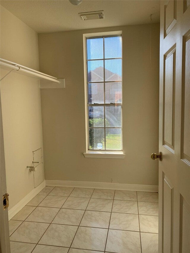 laundry room with baseboards, a healthy amount of sunlight, visible vents, and light tile patterned floors