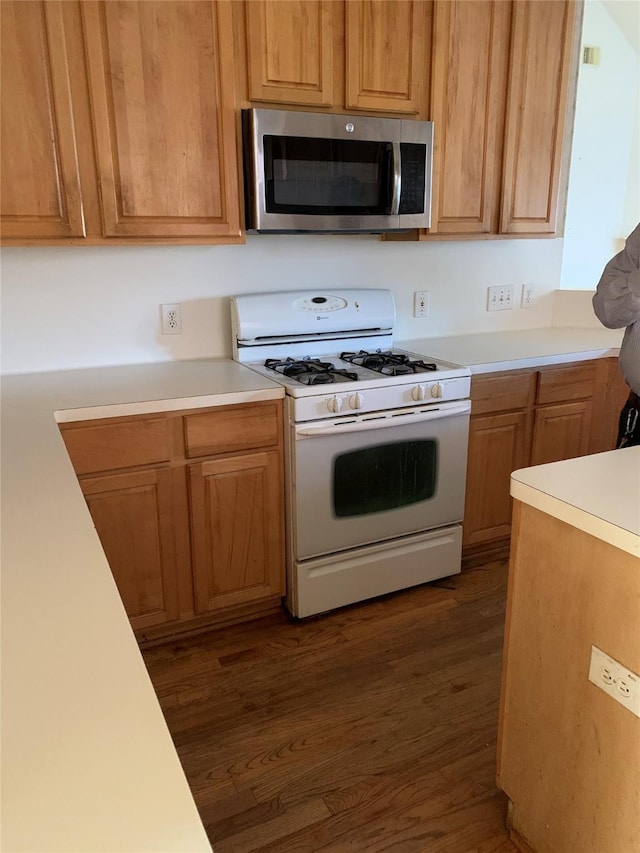 kitchen with white gas range, light countertops, stainless steel microwave, and dark wood finished floors