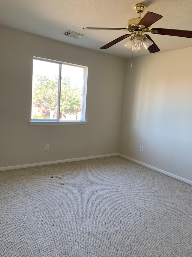 carpeted empty room featuring baseboards, visible vents, and ceiling fan