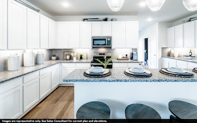 1425 17th Ave N, Texas City, TX 77590 - kitchen with stainless steel appliances, white cabinets, light wood-type flooring, tasteful backsplash, and a breakfast bar area