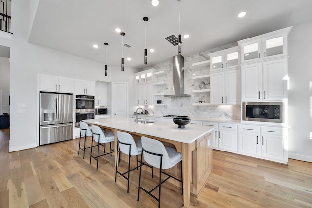kitchen featuring wall chimney range hood, backsplash, appliances with stainless steel finishes, open shelves, and a sink