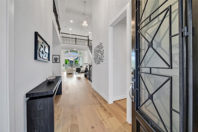 foyer entrance featuring baseboards, light wood-style flooring, and a notable chandelier