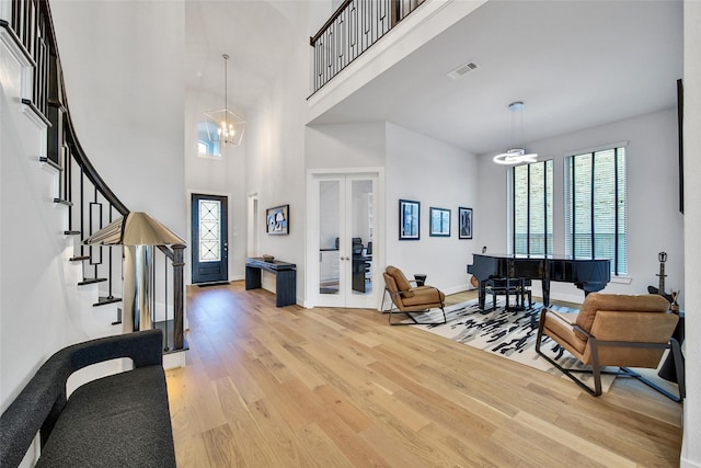 entrance foyer with visible vents, french doors, light wood finished floors, and a towering ceiling