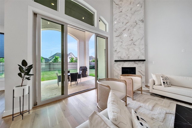living area with light wood-style floors, a fireplace, and a towering ceiling