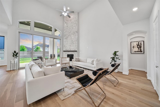 living area with a fireplace, baseboards, high vaulted ceiling, light wood-type flooring, and recessed lighting