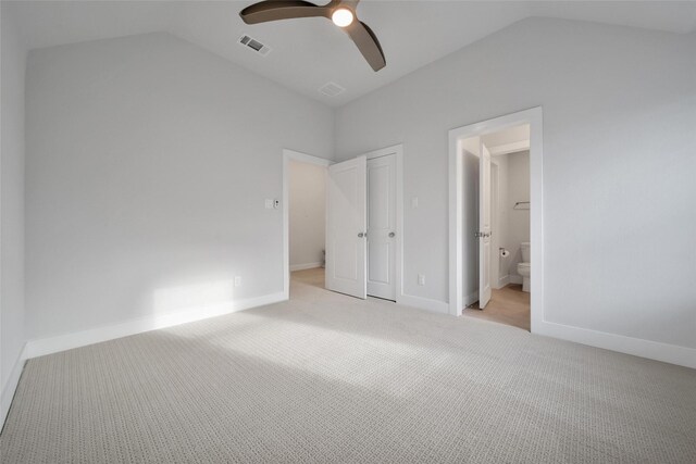 unfurnished bedroom featuring visible vents, ensuite bathroom, ceiling fan, light colored carpet, and vaulted ceiling