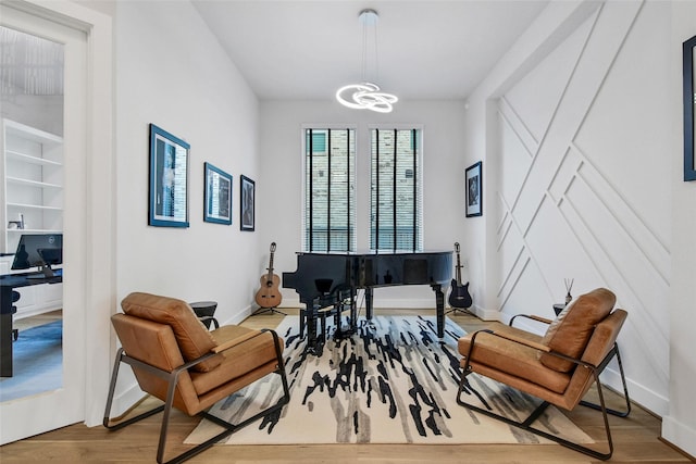 living area featuring baseboards, wood finished floors, and an inviting chandelier