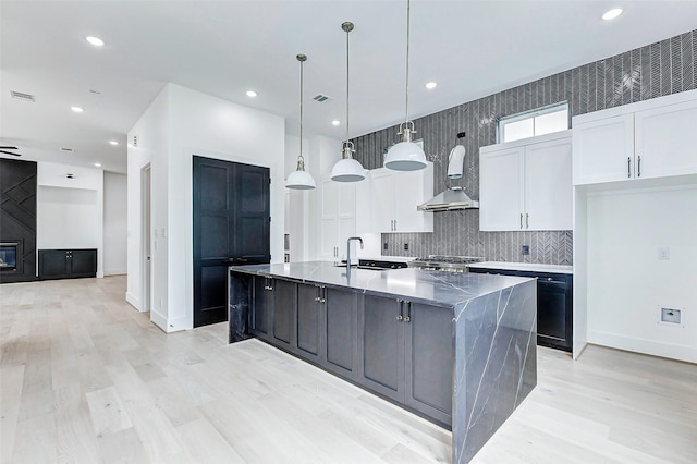 1907 Lauderdale St, Houston, TX 77030 - kitchen with tasteful backsplash, white cabinets, a spacious island, wall chimney exhaust hood, and stove