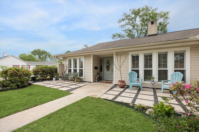 back of property featuring a patio area, a lawn, and a chimney