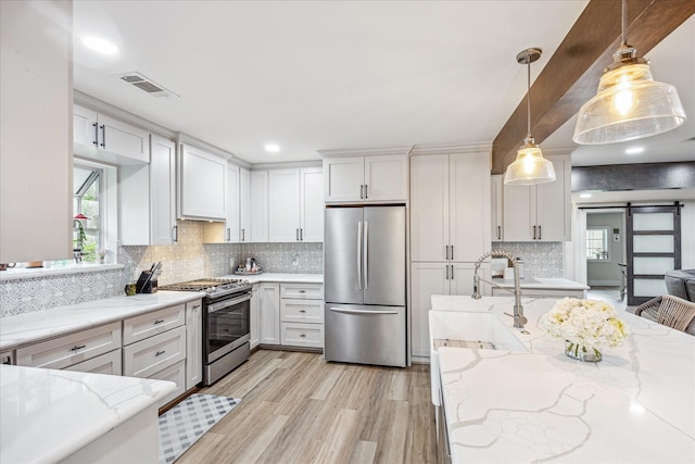 kitchen featuring white cabinets, tasteful backsplash, stainless steel appliances, and a sink