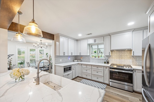 kitchen featuring stainless steel appliances, visible vents, a notable chandelier, and a healthy amount of sunlight