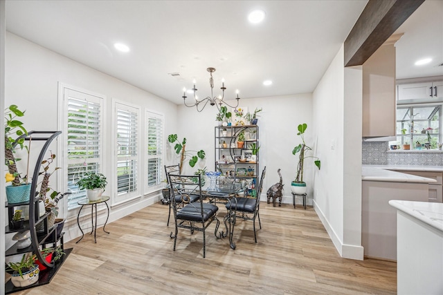 dining space featuring light wood-style flooring, an inviting chandelier, and a healthy amount of sunlight