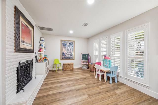 game room featuring a fireplace, wood finished floors, visible vents, and a wealth of natural light