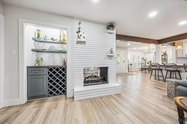 living room with light wood-style floors, an inviting chandelier, a fireplace, baseboards, and recessed lighting