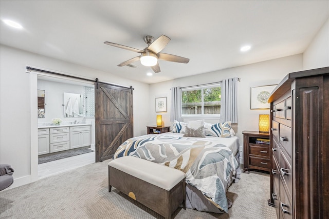 bedroom featuring light carpet, ensuite bathroom, recessed lighting, and a barn door